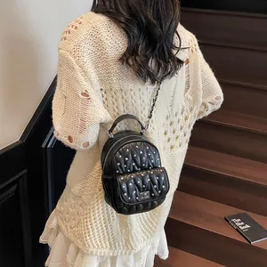 Detail of a black quilted mini backpack with rhinestone studs and chain shoulder straps