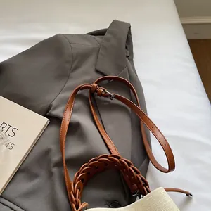 Detail of brown bucket bag showing woven ring strap and adjustable leather shoulder strap