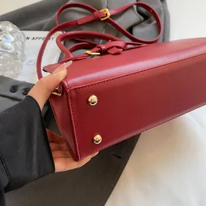 Détail macro du sac en cuir rouge avec quatre clous de protection en métal doré