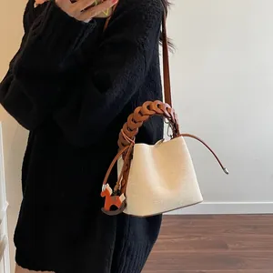 Detail of bucket bag with woven handle, canvas texture, and horse charm decoration