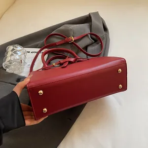 Vue détaillée du fond du sac bordeaux avec quatre pieds de protection en métal doré