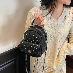 Detail of black quilted mini backpack with sparkling rhinestones and metal chain strap