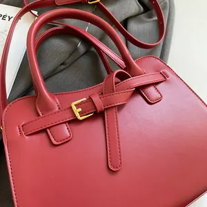 Gros plan détaillé du sac cabas bordeaux avec boucle dorée et texture en cuir poli
