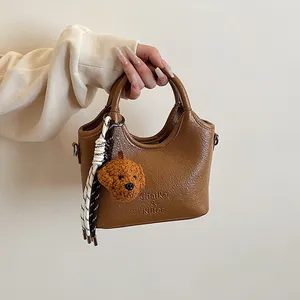 Dettaglio borsa marrone in ecopelle con texture increspata e ciondolo a forma di cane
