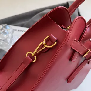 Détail des fermoirs dorés et des coutures sur un grand sac cabas en cuir bordeaux