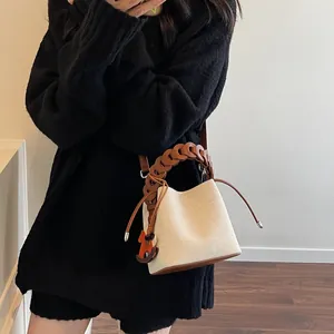 Detail of cream bucket bag with brown woven chain handle and orange horse charm