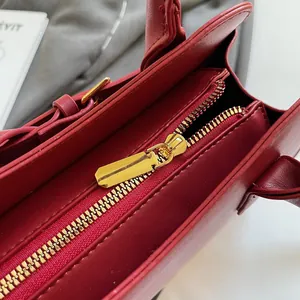 Gros plan sur la fermeture éclair dorée et les coutures d'un sac cabas en cuir rouge