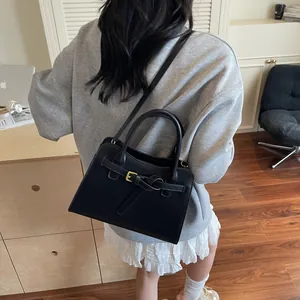 Détail du sac cabas en cuir noir avec boucle de ceinture et longue bandoulière réglable