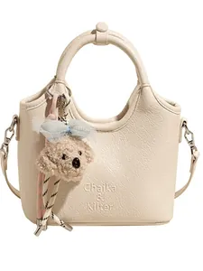 Elegante borsa a secchiello beige con trama litchi e ciondolo a forma di cane carino