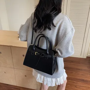 Détail d'un sac cabas noir structuré avec garnitures dorées porté par un mannequin
