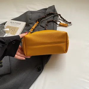 Detail of yellow lychee leather bag featuring silver chain and woven rope strap