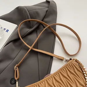 Vue de dessus du sac seau plissé camel avec chaîne dorée sur fond de costume gris