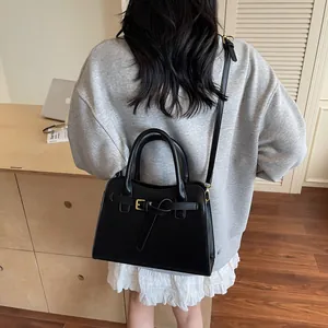 Sac fourre-tout noir minimaliste avec boucle, porté dans un cadre lifestyle chic