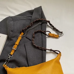 Detail of vibrant yellow crossbody bag with woven rope and silver chain strap