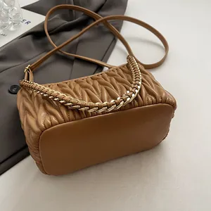 Détail du sac seau marron en cuir plissé Matelassé avec chaîne dorée et texture fine