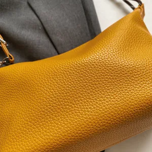 Close-up of mustard yellow pebble leather texture with silver buckle on a women's bag
