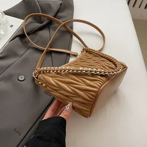Détail du sac seau camel montrant la texture plissée et la bandoulière en chaîne tissée