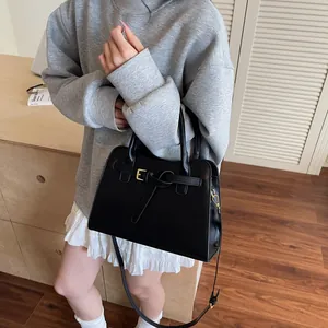 Détail du cabas en cuir noir avec boucles dorées et bandoulière réglable pour le transport