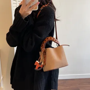 Detail of canvas bucket bag with braided leather handle and orange horse charm
