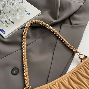 Gros plan d'un sac seau marron clair avec plis et bandoulière en chaîne de métal tressé