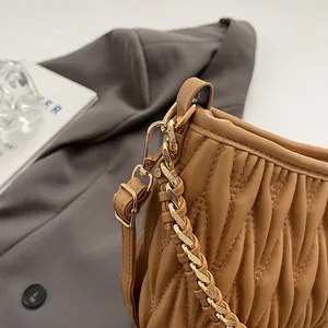 Vue macro du sac seau plissé caramel avec chaîne dorée et cuir synthétique doux