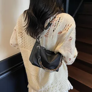 Close-up of black lychee grain leather underarm bag with silver chain and woven strap