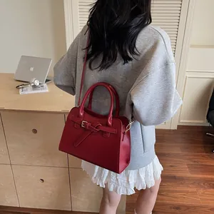 Vue latérale d'un sac cabas en cuir rouge porté par un mannequin dans un bureau urbain
