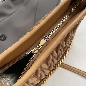 Vue macro d'un sac seau caramel en cuir plissé avec fermeture éclair et chaîne dorée