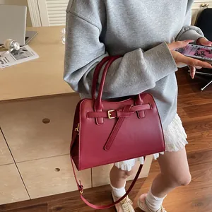 Sac fourre-tout bordeaux porté par un mannequin dans un cadre de bureau chaleureux