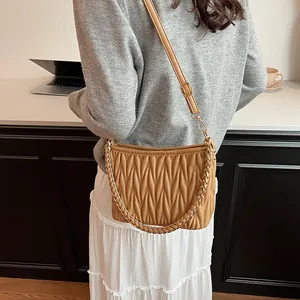 Vue détaillée du sac seau plissé caramel avec chaîne dorée porté par un mannequin