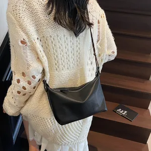 Detail of black pebbled leather crossbody bag featuring unique V-stitch and shoulder strap