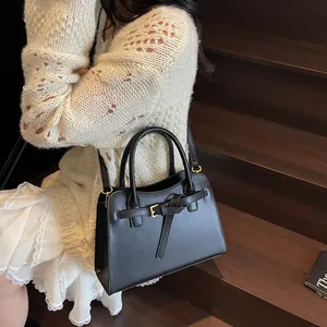 Gros plan d'un sac cabas noir en cuir avec boucle dorée porté par un mannequin en mouvement
