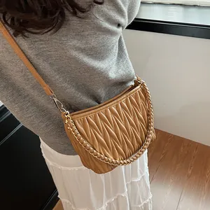 Détail d'un sac seau plissé caramel avec chaîne dorée porté sur l'épaule