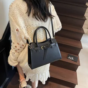 Détail d'un mannequin portant un sac cabas en cuir noir avec boucle dorée en escalier
