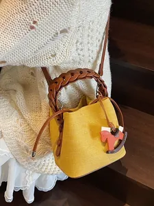 Chic yellow canvas bucket bag with brown woven handle and rocking horse charm on steps