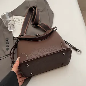 Détail du sac seau en cuir marron grainé avec coutures contrastées et clous de fond