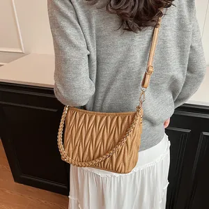 Détail du sac seau plissé kaki avec chaîne dorée et bandoulière en cuir réglable