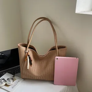 Detail of khaki woven tote bag with herringbone texture and decorative wooden beads