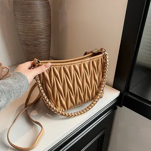 Détail du sac en cuir plissé caramel avec poignée en chaîne dorée et bandoulière chic