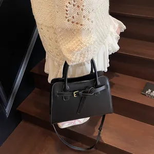 Sac à main noir chic avec nœud décoratif et bandoulière dans un cadre élégant et moderne