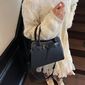 Détail du sac à main en cuir noir avec boucle métallique et bandoulière amovible