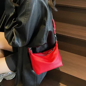 Close-up of red lychee pattern leather handbag with silver metallic buckle on dark wood stairs