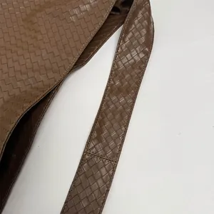 Detailed close-up of dark brown woven leather tote bag with thick interlaced straps