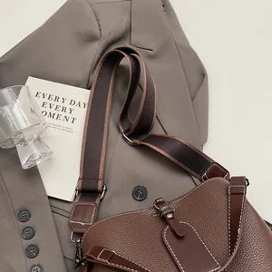 Détail du cuir litchi marron foncé avec coutures blanches contrastées sur le sac seau