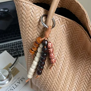 Detail of vintage wooden bead charm with metal clasp attached to a woven tote bag