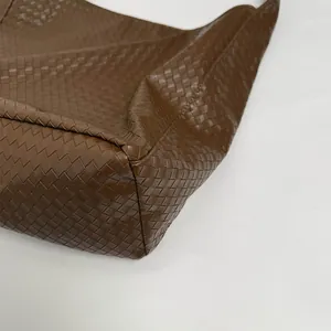 Macro detail of the premium dark brown woven leather texture on the large tote bag corner