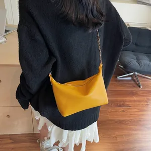Detail of yellow lychee pattern leather shoulder bag with woven strap on a model