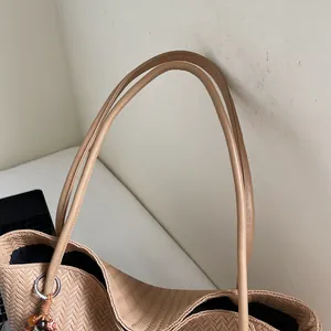 Macro detail of beige woven tote bag showing V-pattern texture and wood bead pendant