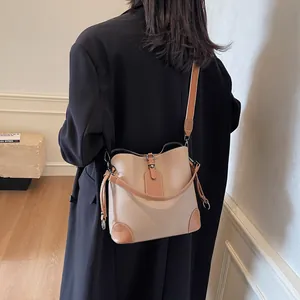 Sac seau en cuir marron et kaki porté par un mannequin pour référence de taille et style