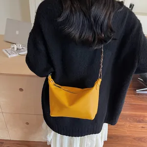 Close-up of yellow pebbled leather crossbody bag with woven black and white rope strap